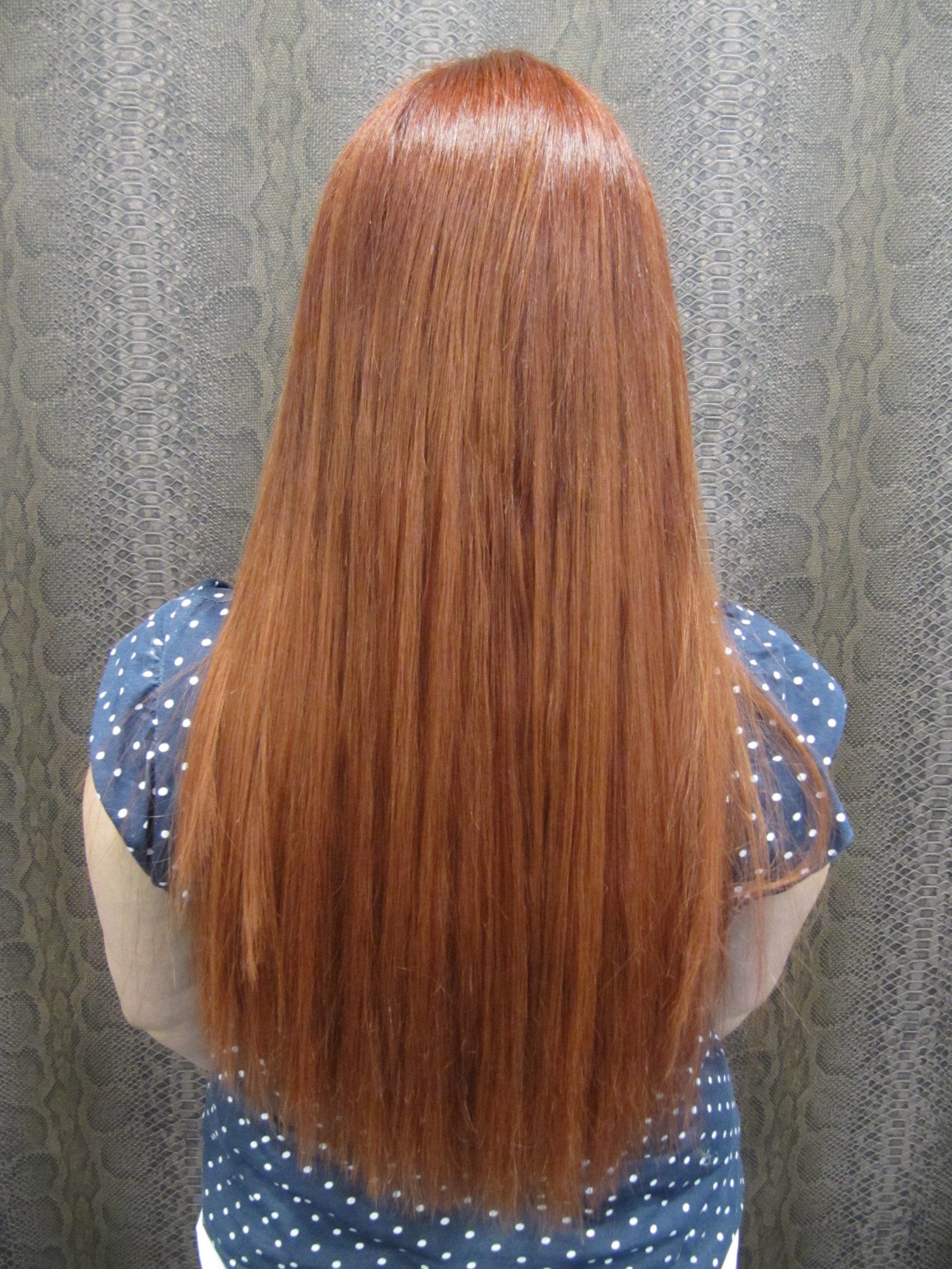 Una mujer con cabello largo y rojo lleva una camisa de lunares azules.