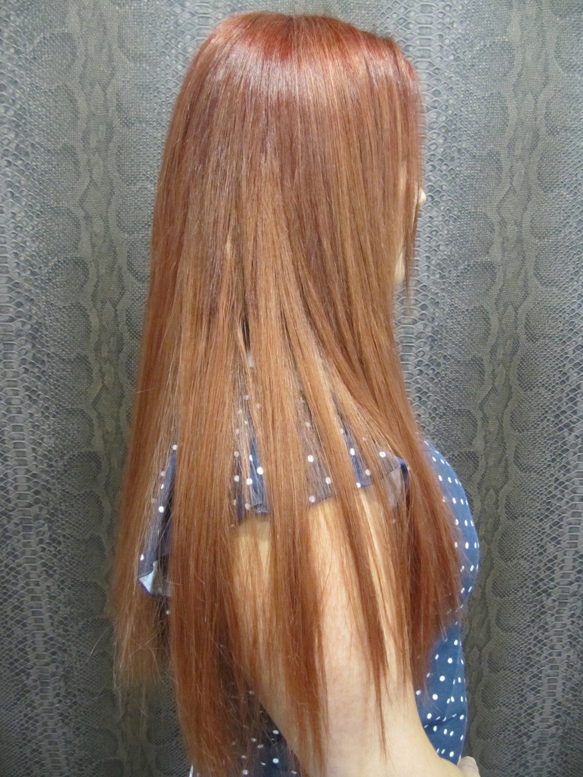 Una mujer con cabello largo y rojo está parada frente a una pared.