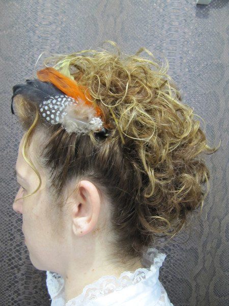 Una mujer con cabello rizado lleva una diadema con plumas.