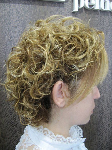 Una mujer con cabello rizado lleva una camisa blanca.