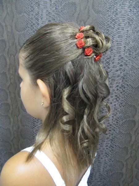 Una niña lleva el pelo recogido en un moño con flores rojas.