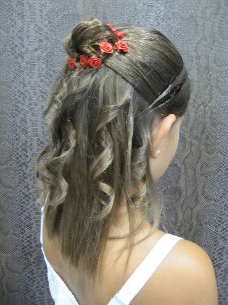 Una niña con un moño y flores rojas en el pelo.