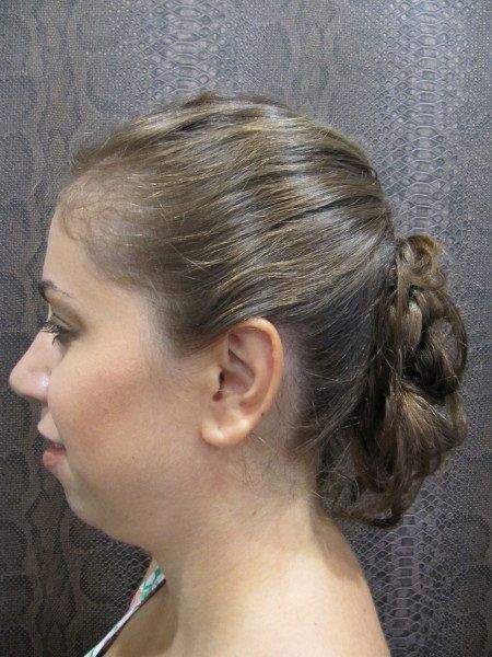 Una mujer lleva el pelo recogido en un moño trenzado.