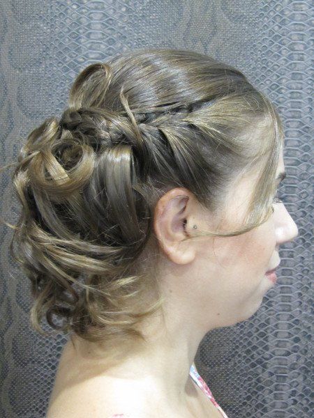 Una mujer con el pelo recogido en un moño está parada frente a una pared.