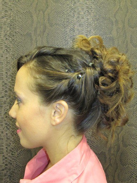 Una mujer con una camisa rosa tiene el pelo recogido en un moño.