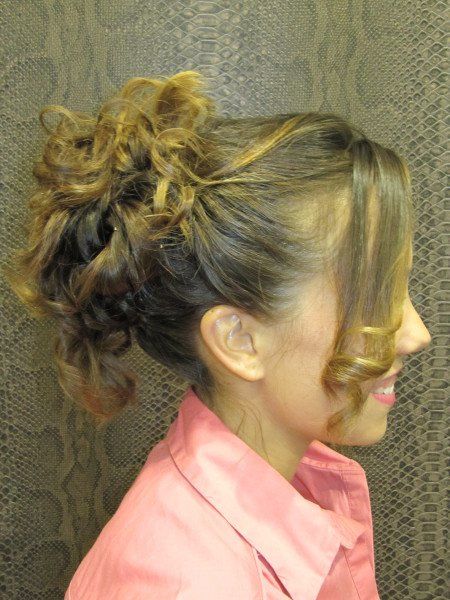 Una mujer lleva una camisa rosa y tiene el pelo recogido en un moño.