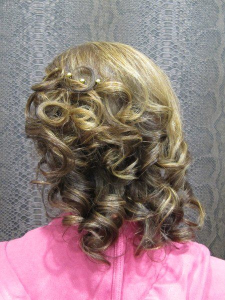 La parte posterior de la cabeza de una mujer con cabello rizado y una camisa rosa.