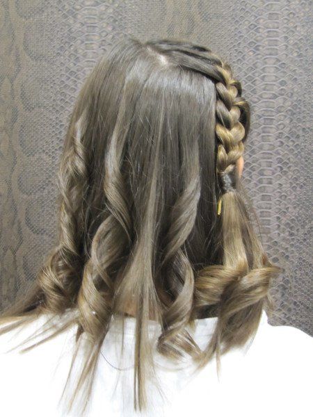 Una mujer con una trenza en el pelo lleva una camisa blanca.