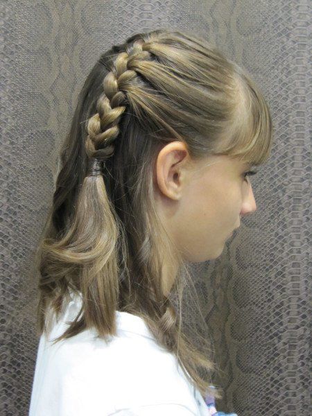 Una chica con una trenza en el pelo lleva una camisa blanca.