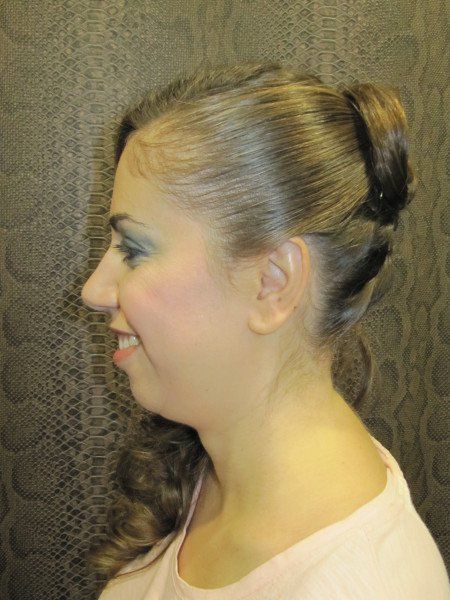 La mujer lleva una camisa rosa y tiene el pelo recogido en un moño.