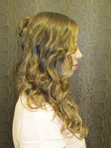 Una mujer con cabello largo y rizado lleva una camisa rosa.