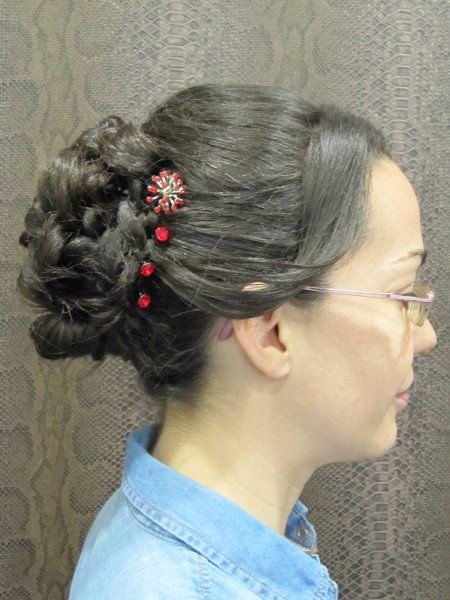 Una mujer que lleva gafas y un moño con una flor en el pelo.