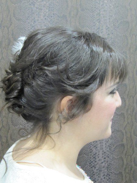 La mujer lleva una camisa blanca y tiene el pelo recogido en un moño.