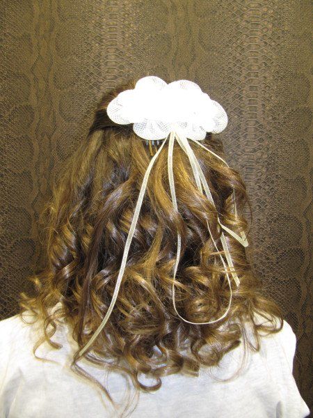 Una mujer con cabello rizado lleva una flor blanca en el pelo.