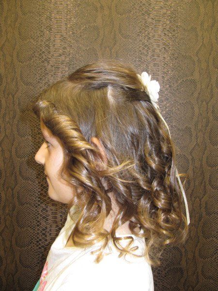 Una niña con cabello rizado y una flor en el pelo.