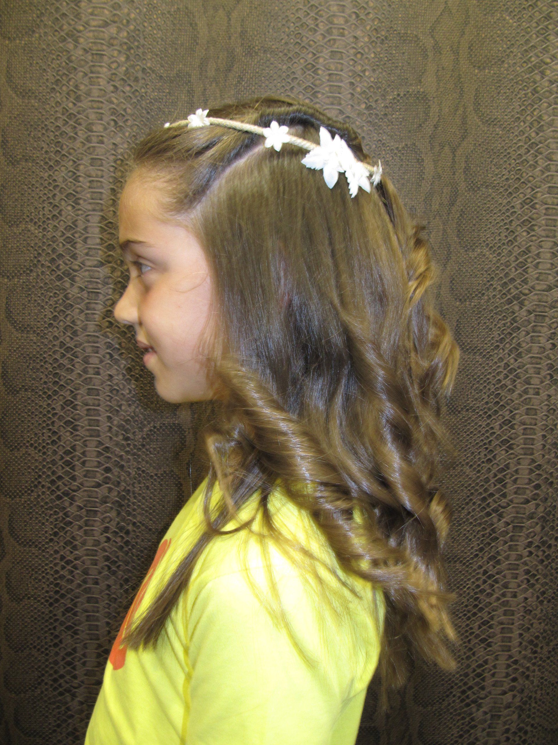 Una niña que lleva una camiseta amarilla y una diadema con flores blancas en el pelo.