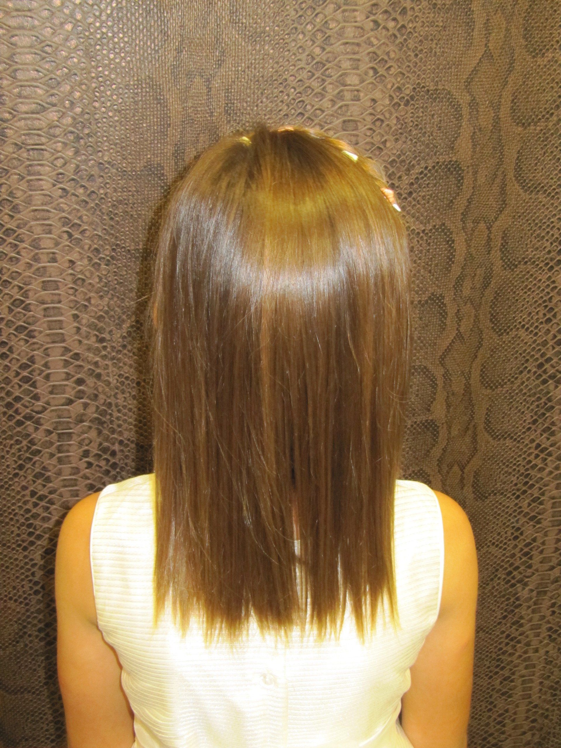 Una mujer con cabello largo y castaño lleva una camiseta blanca sin mangas.