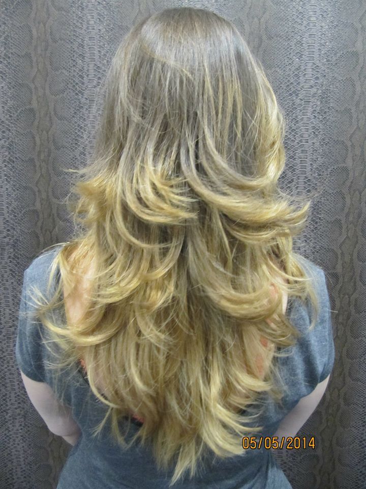 Una mujer con cabello largo y rubio está parada frente a una pared.