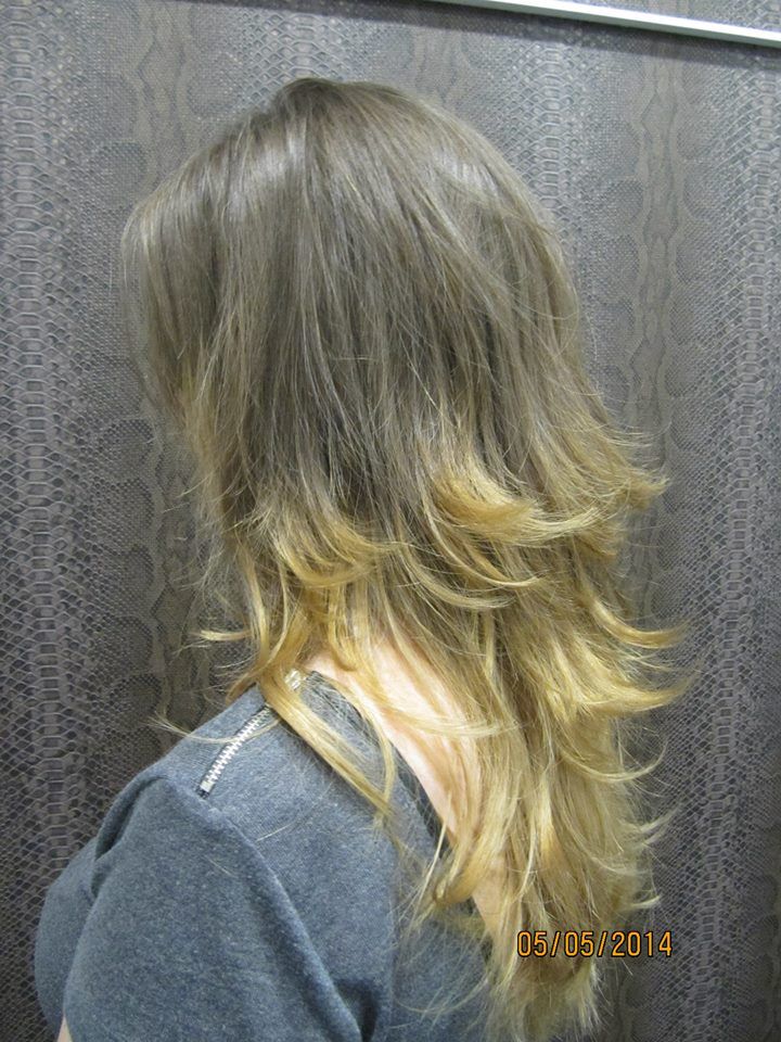 Una mujer con cabello largo y rubio lleva una camisa gris.