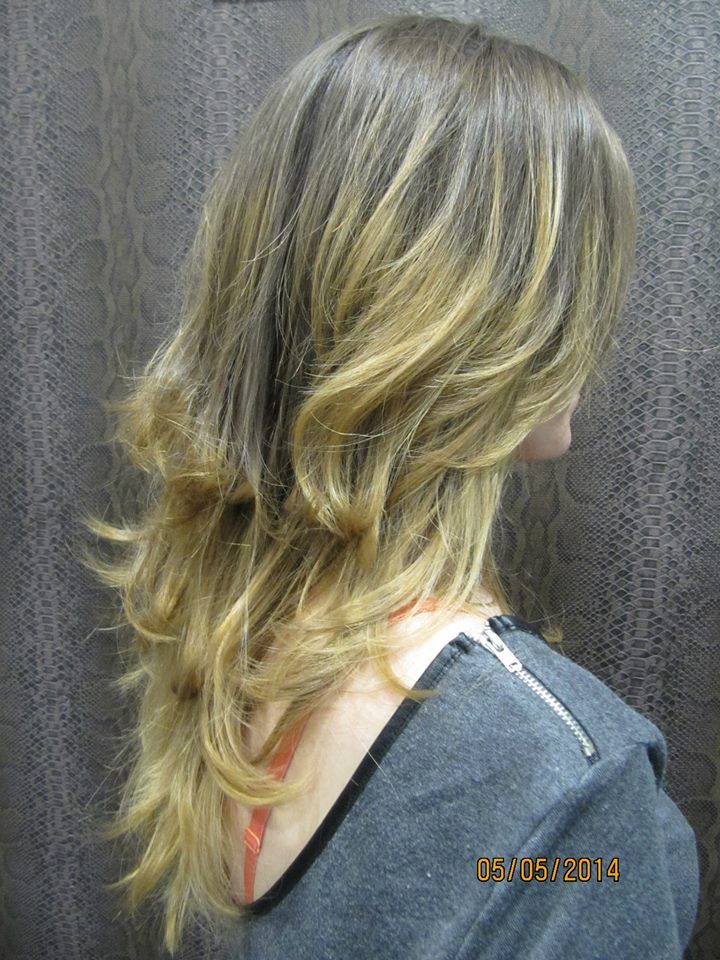 Una mujer con cabello largo y rubio lleva una camisa gris.