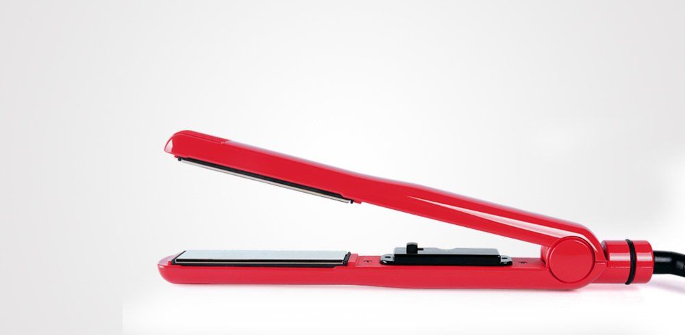 Una plancha de pelo roja está colocada sobre una superficie blanca.