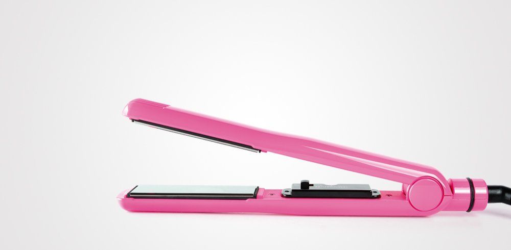 Una plancha de pelo rosa está sobre una superficie blanca.