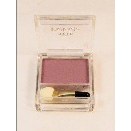 Una sombra de ojos morada en un recipiente transparente con un pincel.