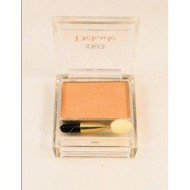 Un recipiente cuadrado de sombra de ojos con un pincel sobre una superficie blanca.