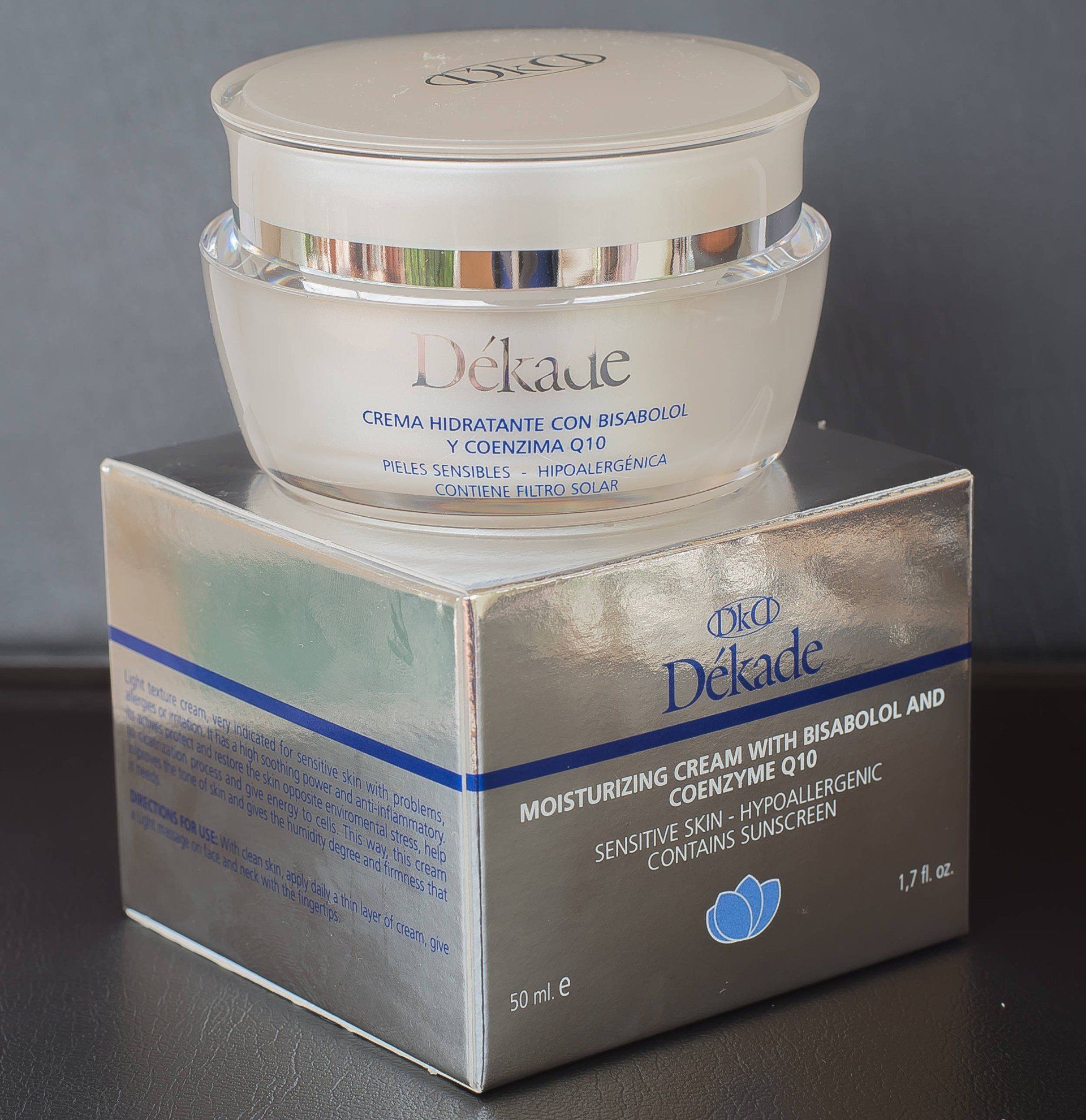 Un frasco de crema hidratante Dekade reposa sobre una caja plateada.