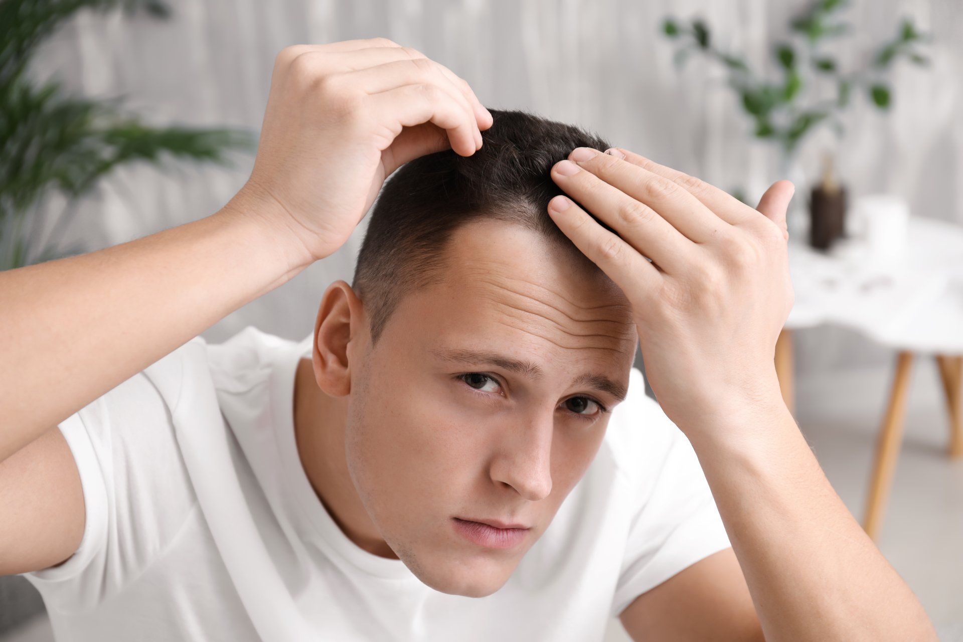 Un joven mira su cabello en una sala de estar.