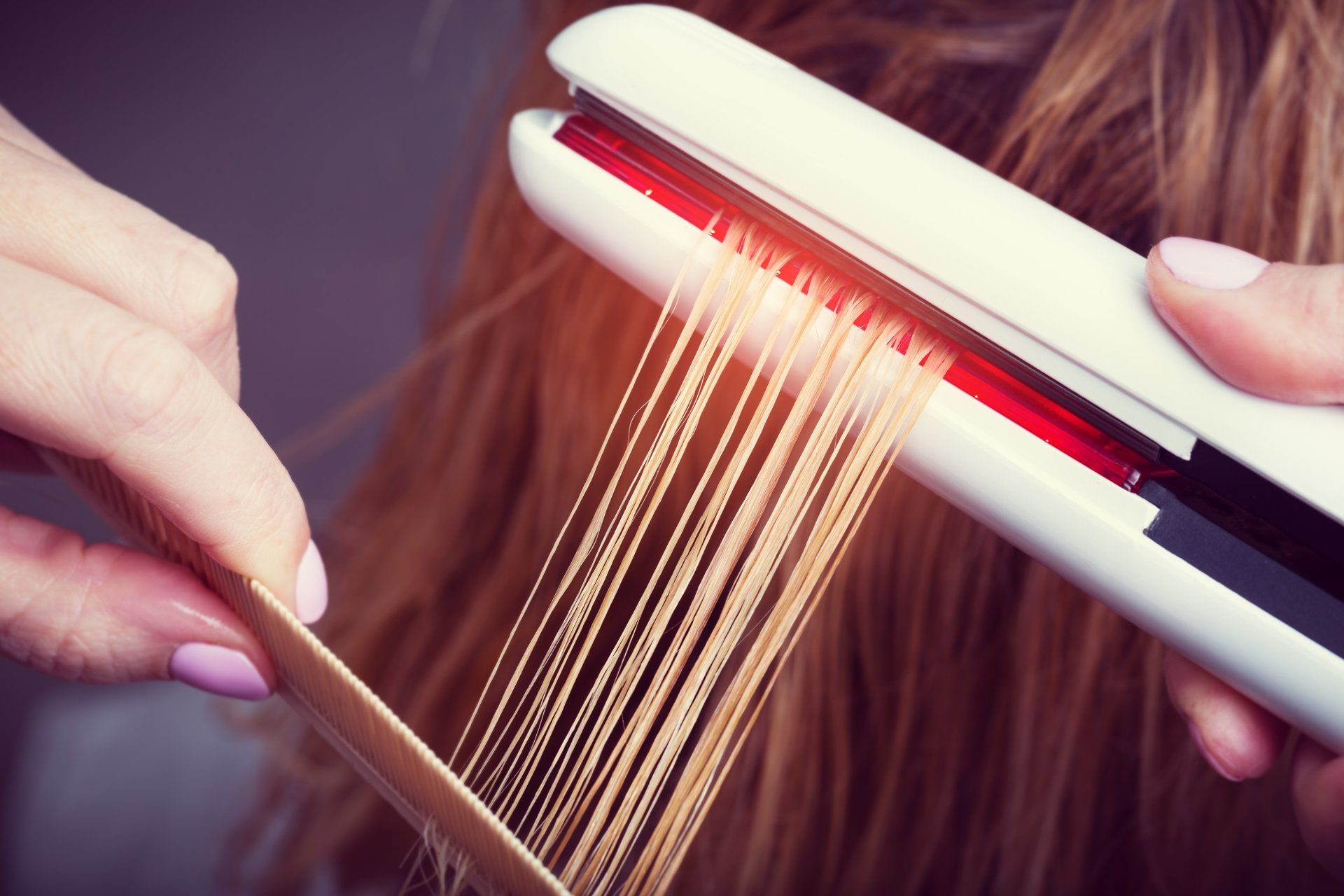 Una mujer se está alisando el cabello con una plancha para el pelo.