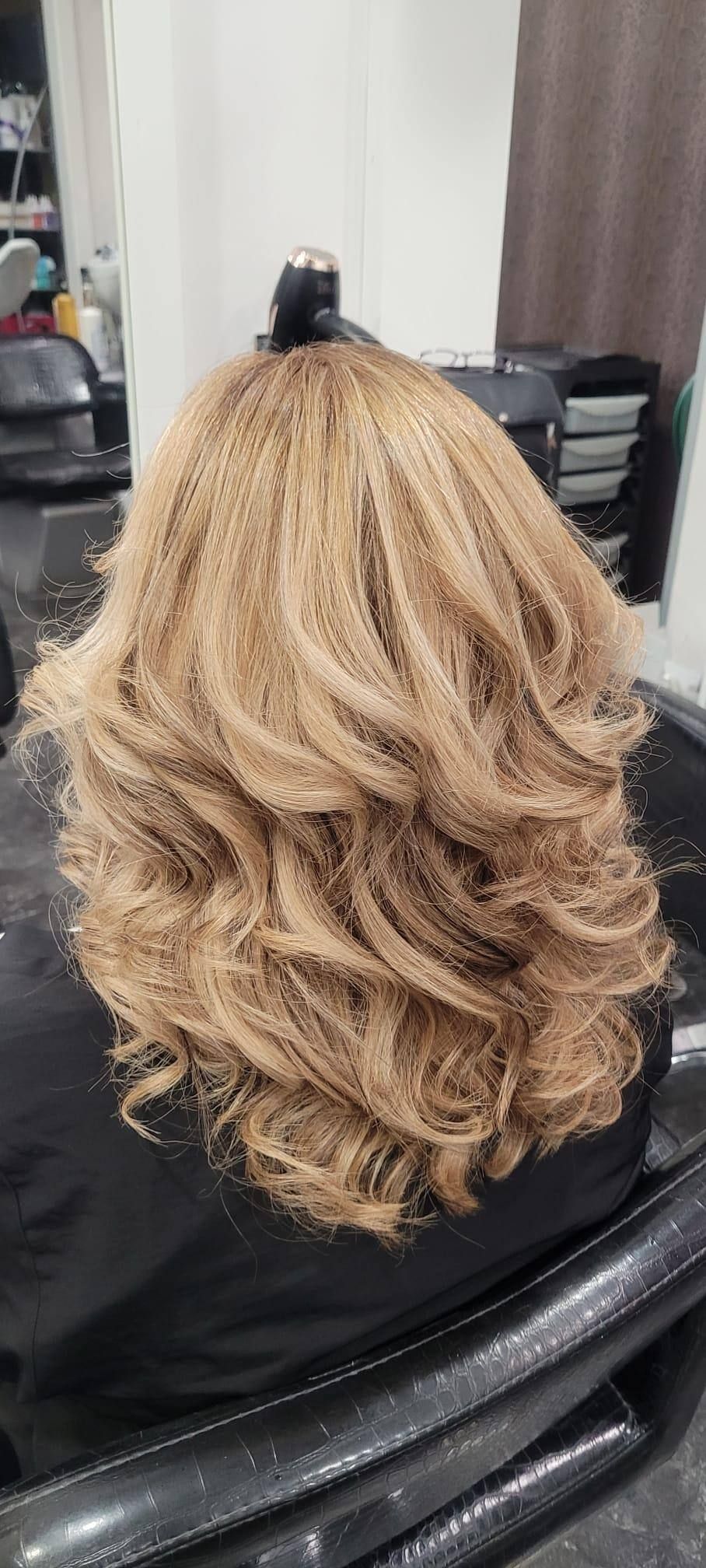 Una mujer con cabello rubio está sentada en una silla en un salón.