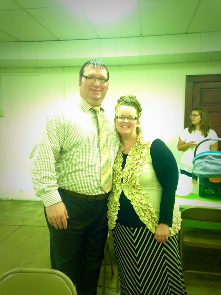 A man and a woman are posing for a picture in a room