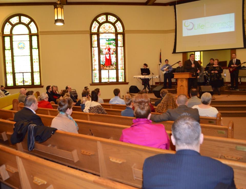 A group of people are sitting in a church watching a presentation