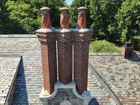 A brick chimney on top of a roof by JW Chimneys in Collegeville PA and surrounding areas.