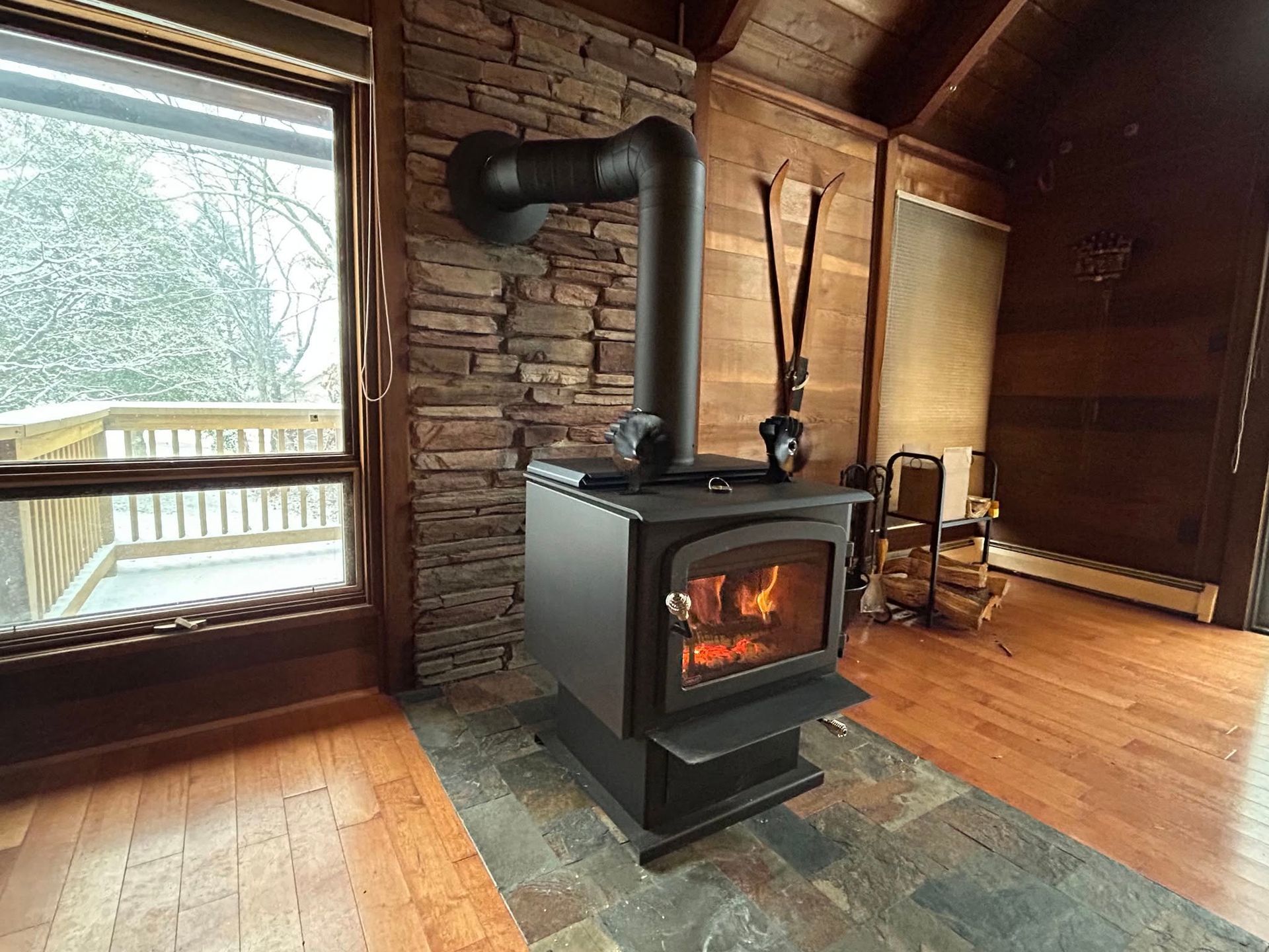 A wood stove is sitting in a living room next to a window.