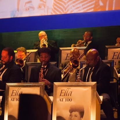 A jazz band performing on stage, with brass and woodwind instruments, with 