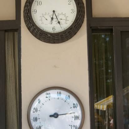 Clock and thermometer mounted on a beige wall.