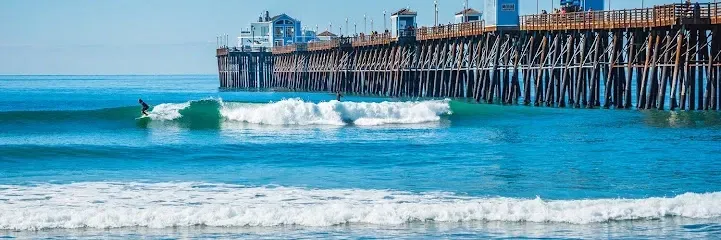 HWH San Diego Hard Money Lender - Real Estate highlights the lifestyle appeal and investment potential of Oceanside Municipal Pier. The image showcases the iconic wooden pier stretching into the Pacific Ocean, surrounded by sandy beaches and coastal views.