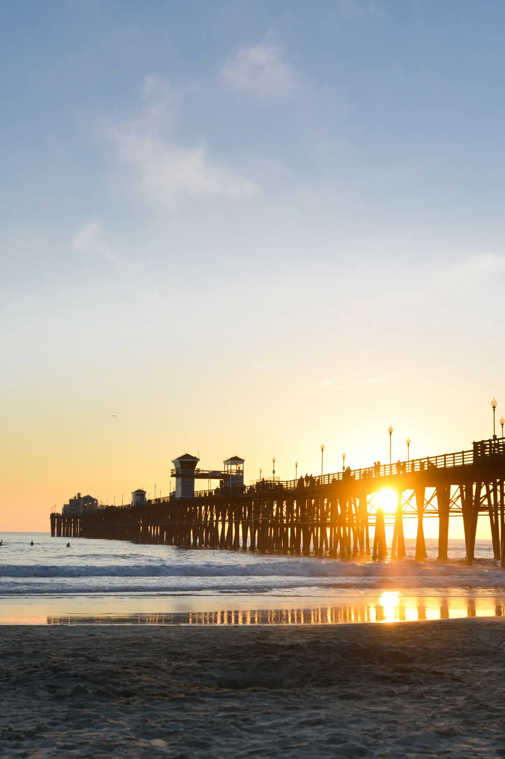 HWH San Diego Hard Money Lender - Real Estate presents a stunning oceanside view from a deck at sunset, with warm colors reflecting across the water.