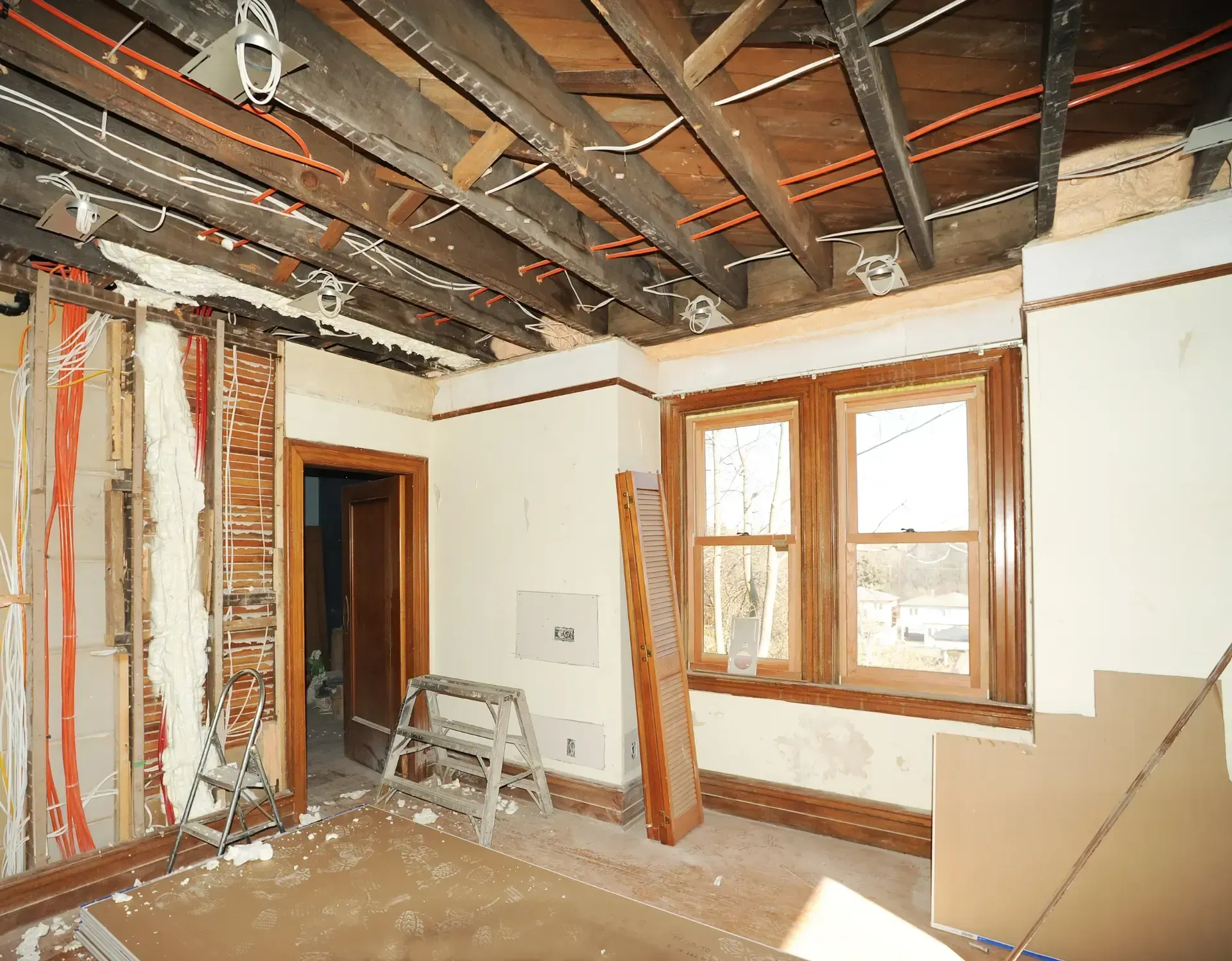 San Diego Hard Money Lender - The photo showcases an unfinished interior with exposed wooden ceiling beams, electrical wiring, and partially removed walls, indicating an active remodeling project.