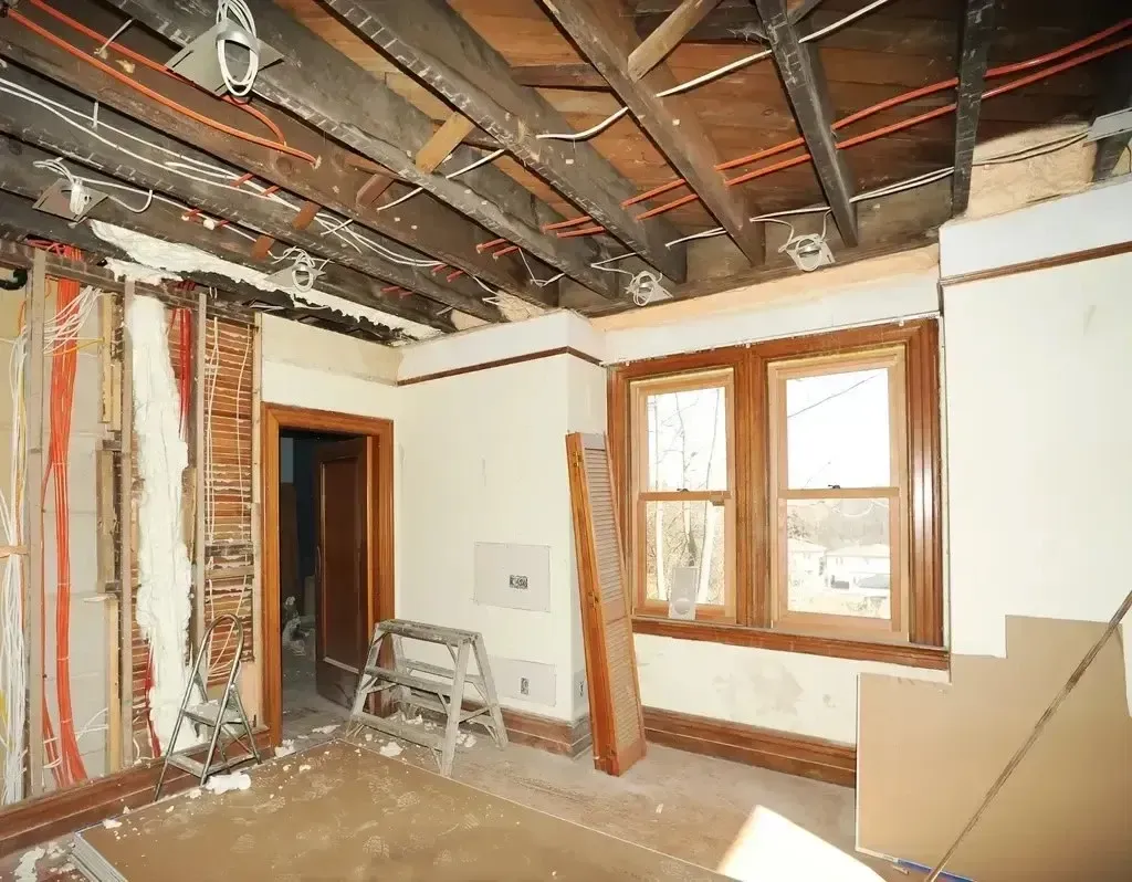 San Diego Hard Money Lender - The photo showcases an unfinished interior with exposed wooden ceiling beams, electrical wiring, and partially removed walls, indicating an active remodeling project.