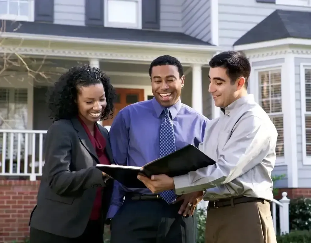 San Diego Hard Money Lender - The image features three professionals reviewing documents in front of a house, highlighting seamless financing solutions.