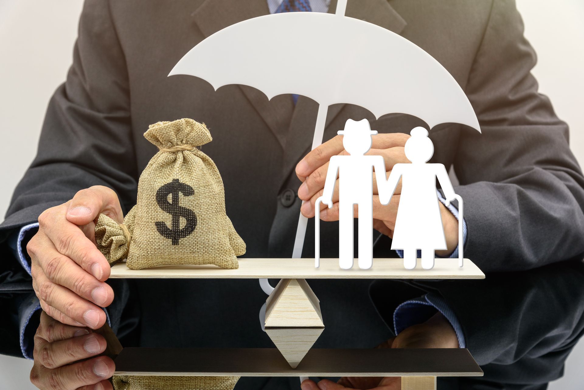 A man is holding an umbrella over a bag of money and an elderly couple.