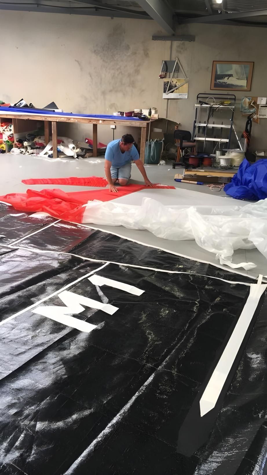 A Man is Working on a Large Piece of Fabric in a Room — Off Shore Sails & Rigging In North Boambee Valley, NSW