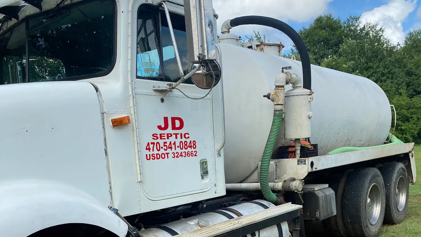 White septic tank truck with JD Septic service logo parked outdoors.