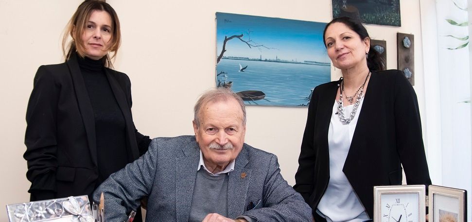 A man and two women are standing side by side in a room.