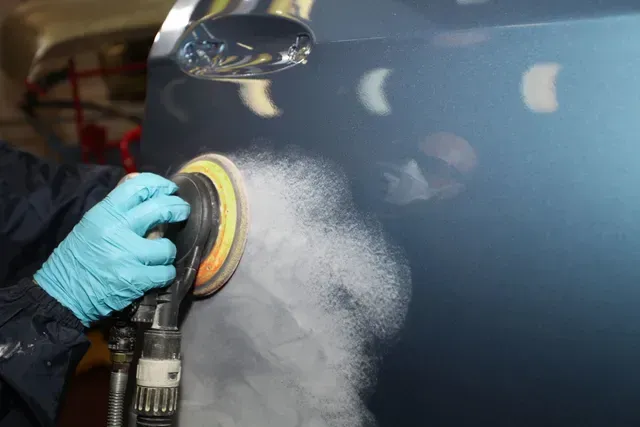 A person is polishing a car with a sander.