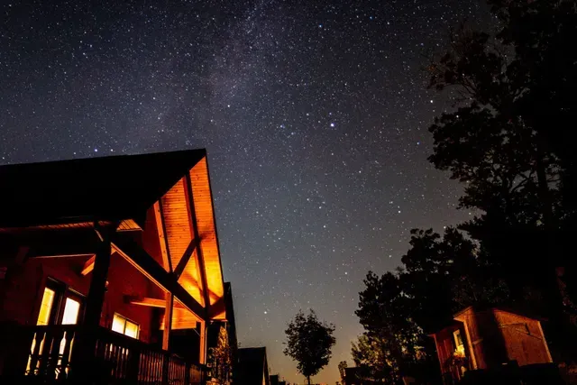 A house is lit up at night under a starry sky