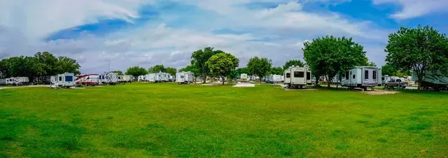 A row of rvs are parked in a grassy field.